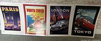 Photo showing the full set of 4 Disney Cars lithographs representing Paris, Porto Corso, London, and Tokyo with vibrant illustrated car scenes.