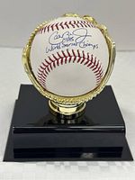 Baseball with signature displayed in gold-tone glove holder on black base
