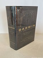 Spine and front cover of 'Darwin: The Indelible Stamp' book with embossed design and gold lettering