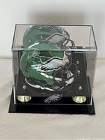 Miniature Philadelphia Eagles football helmet signed by Donovan McNabb inside clear display case with black base and gold-tone stands.