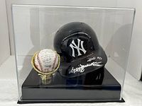 Acrylic display case containing the signed Yankees helmet and signed baseball on black base