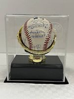 Full view of signed baseball in acrylic display case on black base