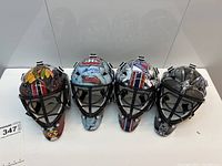 Front view of four NHL team goalie masks lined up