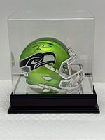 Side view of mini helmet inside acrylic case showing team logo and autograph