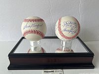 Two signed baseballs displayed on mirrored wood base with plexiglass cover