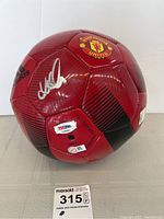 Red Adidas soccer ball displaying Manchester United crest and David Beckham signature