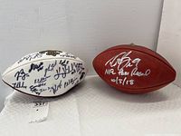 Front view of both footballs showing white roster ball and brown Drew Brees ball