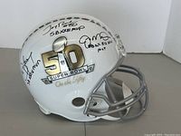 Side view of white helmet showing Super Bowl 50 logo, facemask and two signatures