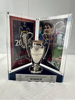 Three-panel acrylic display open, showing central trophy replica and side panels