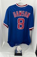 Jersey hung on hanger with baseball display case at base.