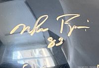 Close-up of gold painted signature reading “Mike Rozier 83” on black helmet shell