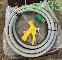 Grey garden hose coiled with yellow spray nozzle and brass fittings on ends