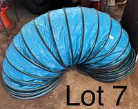 Teal colored collapsible dog agility tunnel shown coiled with black spiral wire supports visible.