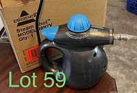 Handheld Bissell Steam Shot steam cleaner in black with blue cap, alongside original box.