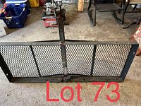 Overview of rectangular black metal mesh cargo carrier with steel frame on concrete floor.