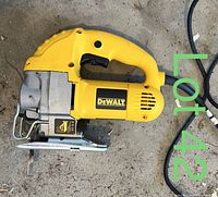 Side view of yellow DeWalt electric jigsaw resting on concrete floor, showing the handle, trigger, and blade clamp assembled with a blade installed.