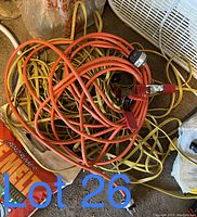Photo showing tangled orange and yellow extension cords with multi-outlet end plugs and standard ends.