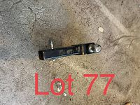 Photo of a black metal trailer hitch with an attached trailer ball on a concrete floor.