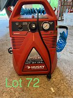 Front view showing control panel with pressure gauge, pressure regulator, and safety valve with Husky branding and model info.