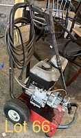 Front right angled view of pressure washer unit showing hose coiled on handle, engine fuel tank, metal frame with wheels and handle