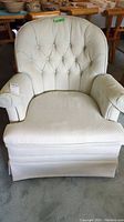 Front view of upholstered armchair showing tufted backrest, seat cushion, and fabric arm covers with slight staining.