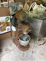 Front side view showing the rusty Hobart commercial mixer with mixing bowl and paddle inside.