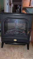 Full view of Electralog electric fireplace heater with faux wood logs and black body.