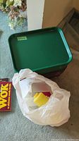 Stack of green and brown cafeteria trays beside a plastic bag containing condiment bottles with one yellow squeeze bottle visible