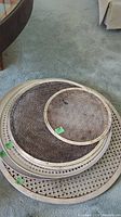 Top view of multiple round metal mesh pizza pans in varying sizes stacked on carpeted floor.