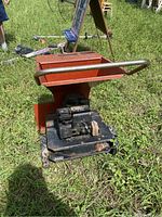 View of front and right side of orange Sears brush chipper/shredder with engine and wheels on grass.