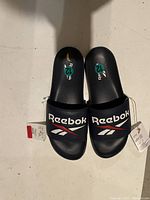 Pair of men's size 12 black Reebok slide sandals with tags attached