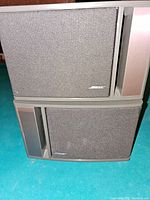 Pair of Bose Model 141 speakers stacked on a floor with grey fabric front and casing