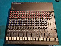 Full top view of mixer showing all 16 channels, faders, knobs and toner splatter.
