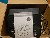 Top view of Combo Album Scanner box showing the user manual with model illustration on top of the scanner unit inside the box.