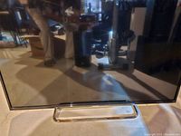 Front view of the Sony 50-inch 3D television on its stand, screen off showing reflection of room.