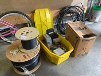 Photo showing the full lot with spools of coaxial cable, yellow bin filled with hardware, a bicycle wheel, and a cardboard box.