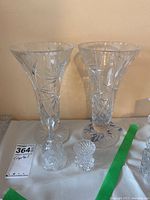 Photo of two pinwheel patterned crystal vases, small crystal bell, and miniature vase on table.
