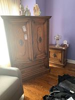 Front view of wooden dresser with two large drawers and two-door cabinet above. Decorative carvings on sides and ornate metal handles.