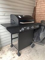Front and side view of the Nexgrill propane barbecue grill showing the four control knobs, side burner, and wheels.