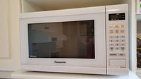 Front view of white Panasonic NN-ST632W microwave with digital keypad and display.