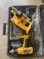 Two DeWalt cordless power tools - drill and circular saw - inside black carrying case, showing general wear and usage marks.