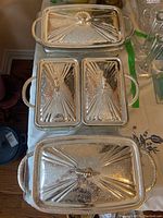 Top view of three silver-tone serving trays with decorative lids and handles, two with Pyrex inserts and one divided tray.
