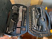 Full view of open black plastic carry case with organized assortment of combination wrenches, sockets, socket ratchets, and extensions.