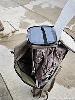Folded brown Woods canopy in a brown carrying case with a solar panel attached to the top of the folded canopy material.