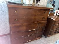 Wide view of the Bassett wood dresser showing five drawers with brass hardware and signs of wear.