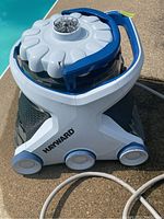 Main robotic pool vacuum on pool deck near water edge