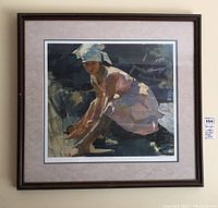 Framed artwork showing a woman in a headscarf crouching, displayed on a wall.