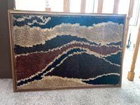 Full view of mid century modern framed rug art piece showing abstract patterned design in brown, tan, cream, black colors.