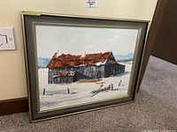 Framed painting of rustic barn with rusted roof in snow, signed Nancy Maxwell