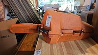 Closed orange plastic Stihl carrying case with metal latch